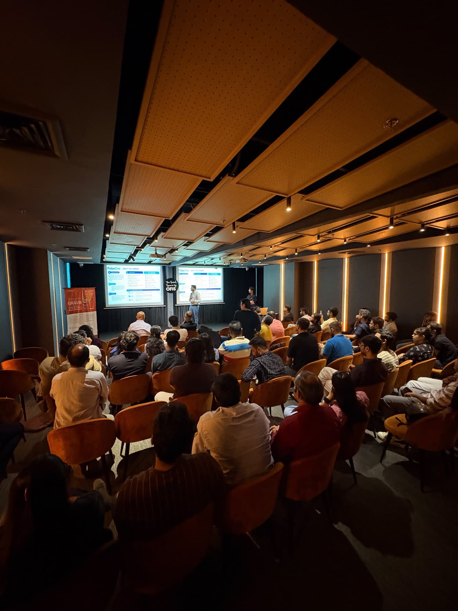 A packed room of founders facing the stage during a startup presentation.